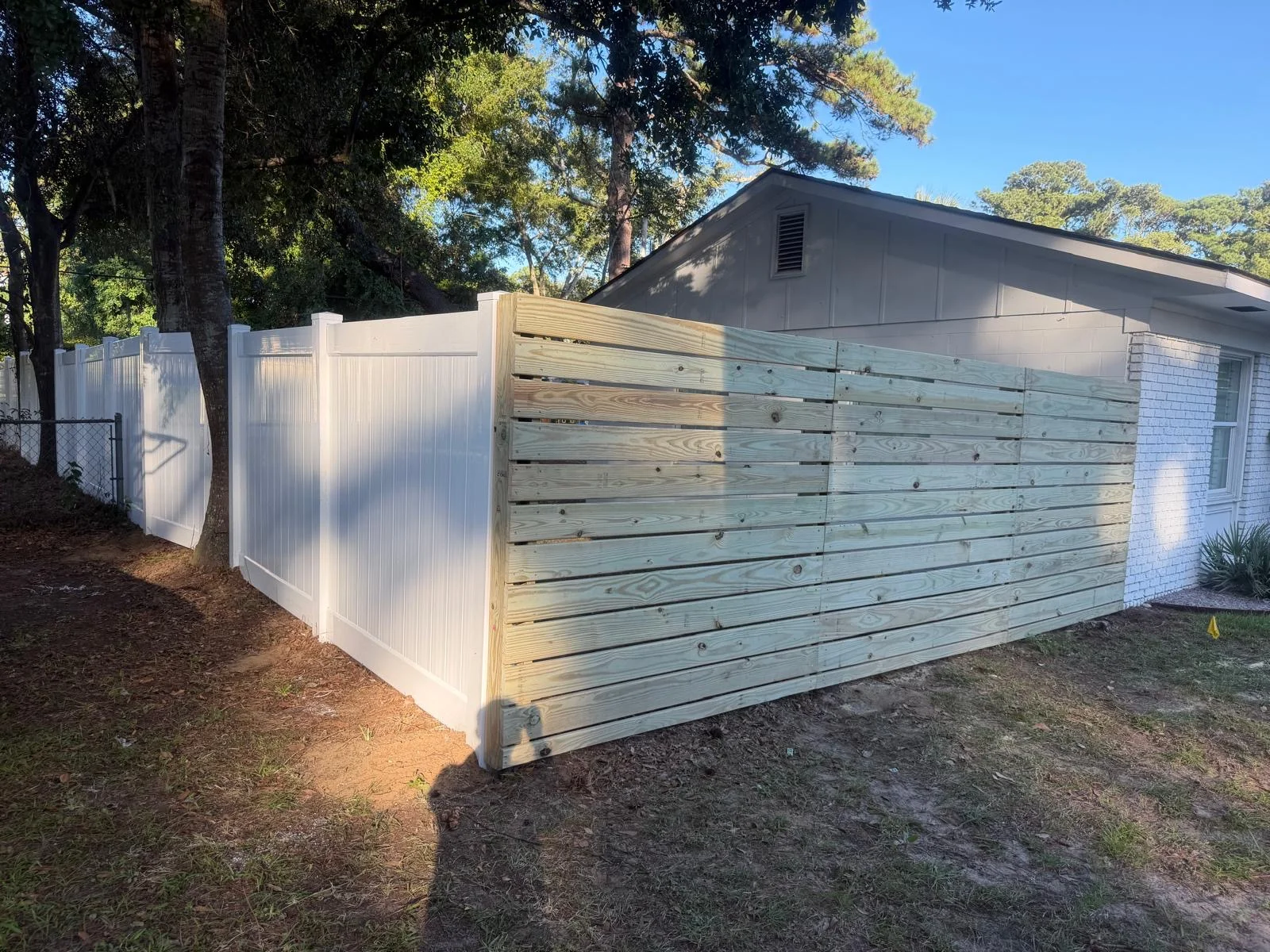 Horizontal wood fence meeting white vinyl privacy fencing