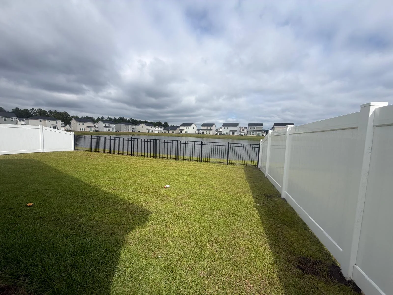 Backyard enclosed with white vinyl privacy and black aluminum fencing