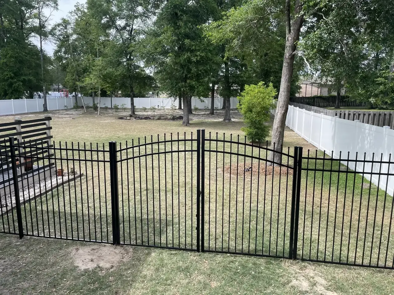 Black aluminum double gate with white vinyl fencing