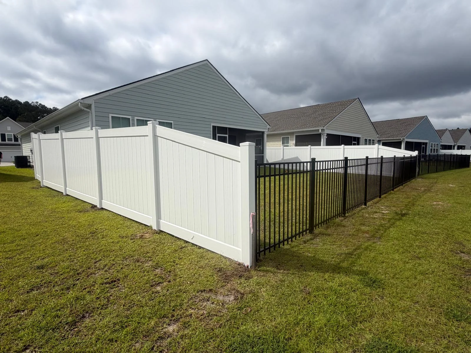 White vinyl privacy fence transitioning to black aluminum fencing