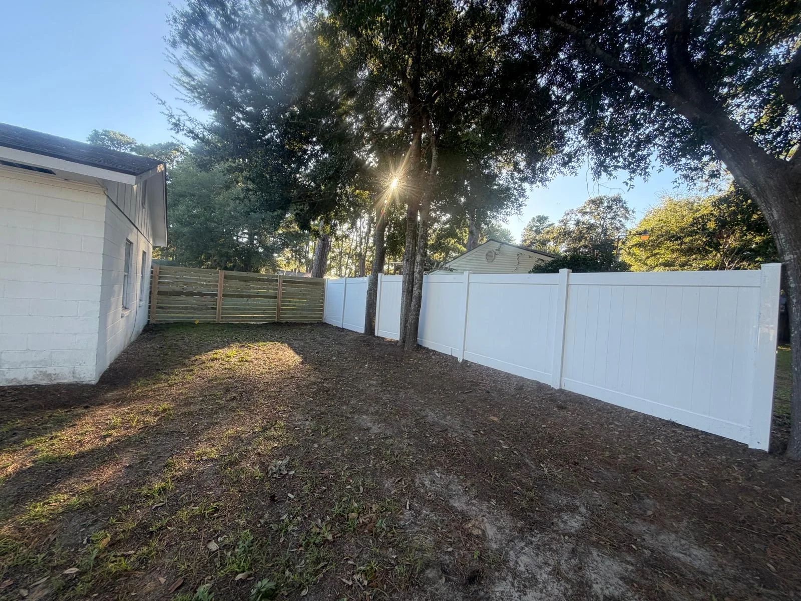 Backyard enclosure with white vinyl and horizontal wood fencing